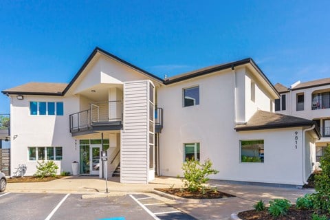 a white building with a balcony and a parking lot